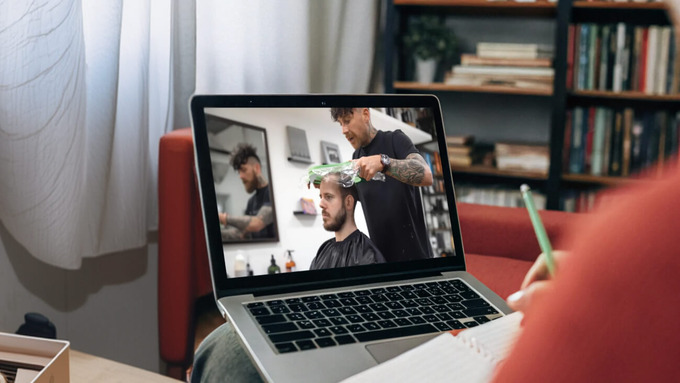 Person watching a hair system attachment tutorial video at home