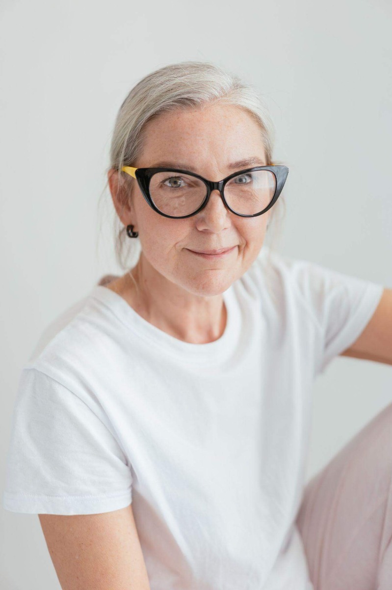 Grey-haired woman sat down with side-swept bangs