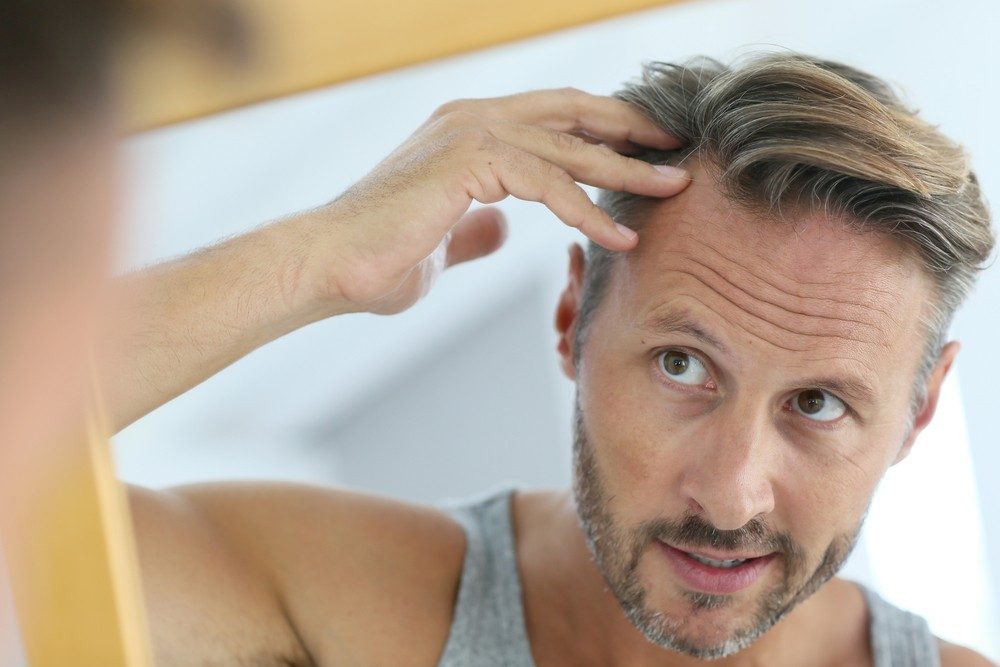 Man inspecting his hairline in the mirror