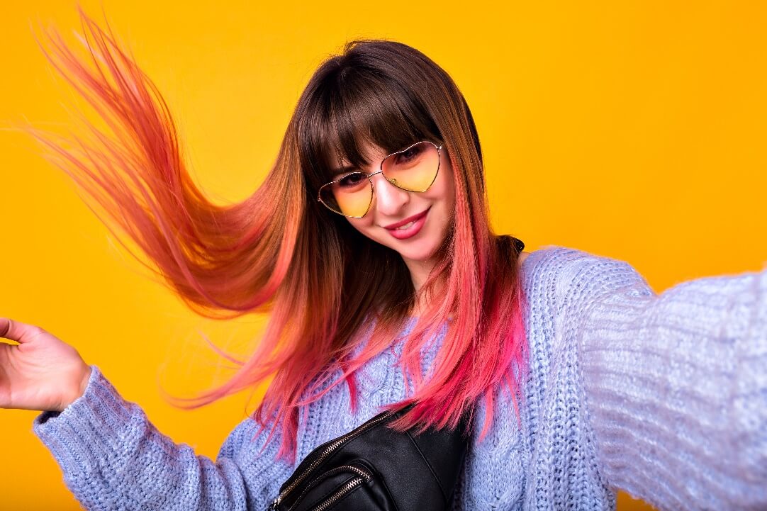 Smiling dark-haired woman with pink roots 